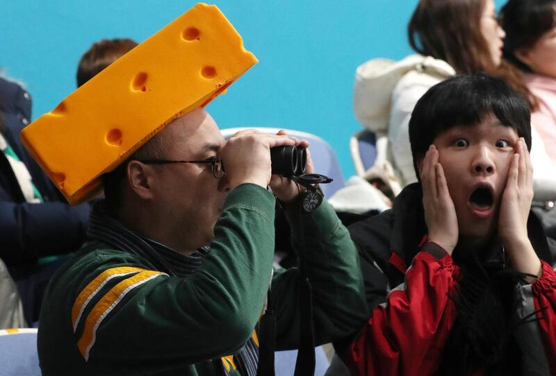 A US fan wearing a cheese hat watches the curling through binoculars as another fan reacts at the Gangneung Curling Centre. Javier Etxezarreta / EPA