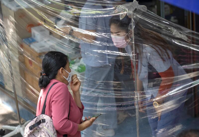A customer orders medicine through plastic sheets in front of pharmacy in Bangkok, Thailand. AP Photo