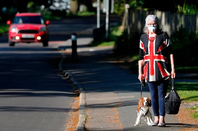 Carol Service wearing a protective face mask, walks her cavalier king charles spaniel on the 75th anniversary of VE Day (Victory in Europe Day), the end of the Second World War in Europe in Hartley Wintney, west of London on May 8, 2020. / AFP / Adrian DENNIS
