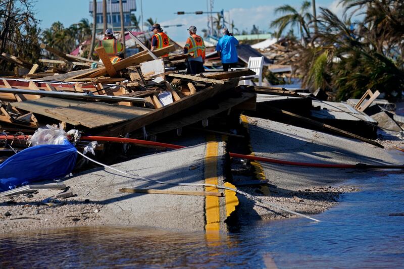 Responders from the de Moya Group look at damage to the bridge. AP