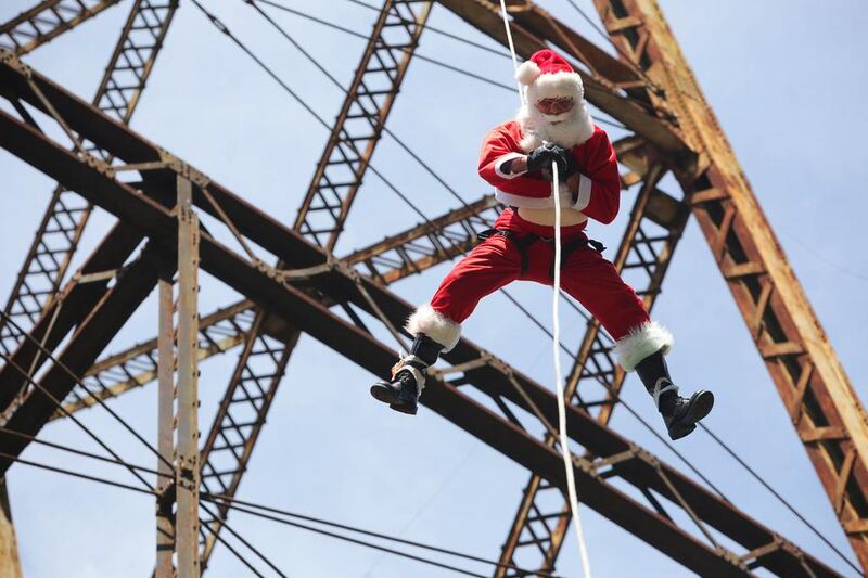 Guatemalan firefighter Hector Chacon, wearing a Santa Claus outfit, rappels down the Belize bridge to give toys to children living under the bridge, in Guatemala City. Mr Chacon has arranged for firefighters to dress as Santa Claus and give out toys during Christmas to children living in the poor neighbourhood under the bridge for the past 17 years. Josue Decavele / Reuters