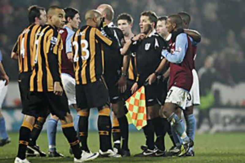 Players surround the referee Steve Bennett as he backtracks on his original decision to give a penalty to Hull after he consulted his assistant.