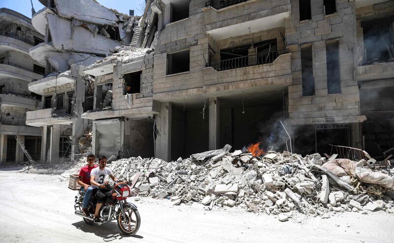 Men ride a motorcycle past debris outside a hospital damaged after a reported air strike in Jisr al-Shughur in the northeastern Syrian Idlib province on July 10, 2019. Regime air strikes on July 10 killed several civilians including children in the town of Jisr al-Shughur, said the Britain-based Syrian Observatory for Human Rights, which relies on a network of sources inside the country. The raids are the latest in an uptick in government and Russian bombardment since late April on the jihadist-administered region of Idlib despite a months-old truce deal. / AFP / Omar HAJ KADOUR
