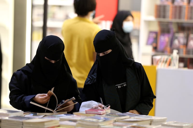 Two Saudi women look at a book during the Riyadh International Book Fair.