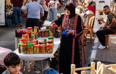 A Palestinian woman in a traditional tatriz dress sells pickles at a shopping and entertainment bazaar organized by the municipality in the West Bank city of Ramallah. AFP