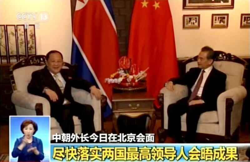 In this image taken from video footage by China's CCTV via AP Video, Chinese State Councilor and Foreign Minister Wang Yi, right, talks to North Korea Foreign Minister Ri Yong Ho during their meeting in Beijing, Tuesday, April 3, 2018. Wang told North Korea's foreign minister on Tuesday that Beijing supports the North's planned summits with South Korea and the United States.  The words at bottom read " Implement the leaders of the two countries (the U.S. and North Korea) have achievement as soon as possible. (CCTV via AP Video)