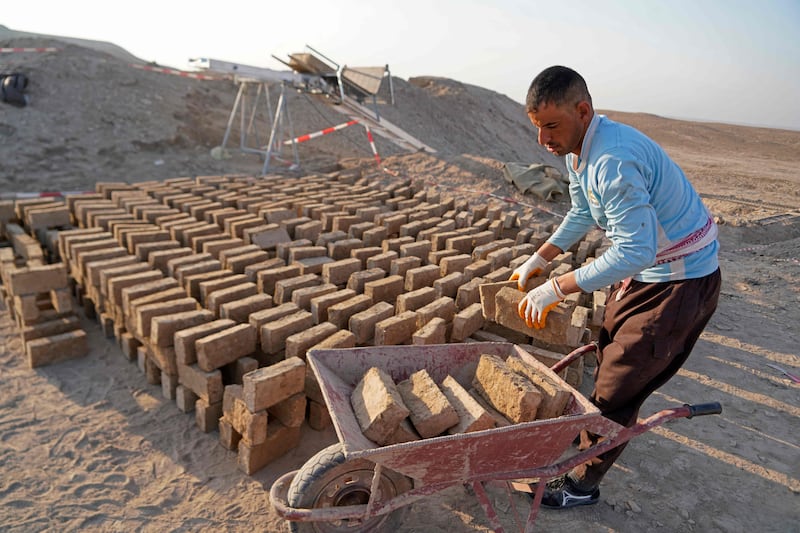 A worker transports traditionally made clay bricks during a German-Iraqi archaeological expedition in Iraq.