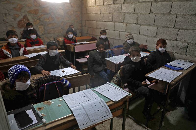 Syrian schoolchildren wearing masks sit in a makeshift school set up by locals in the village of Ma'arin, in the rebel-controlled northern countryside of Syria's Aleppo province.