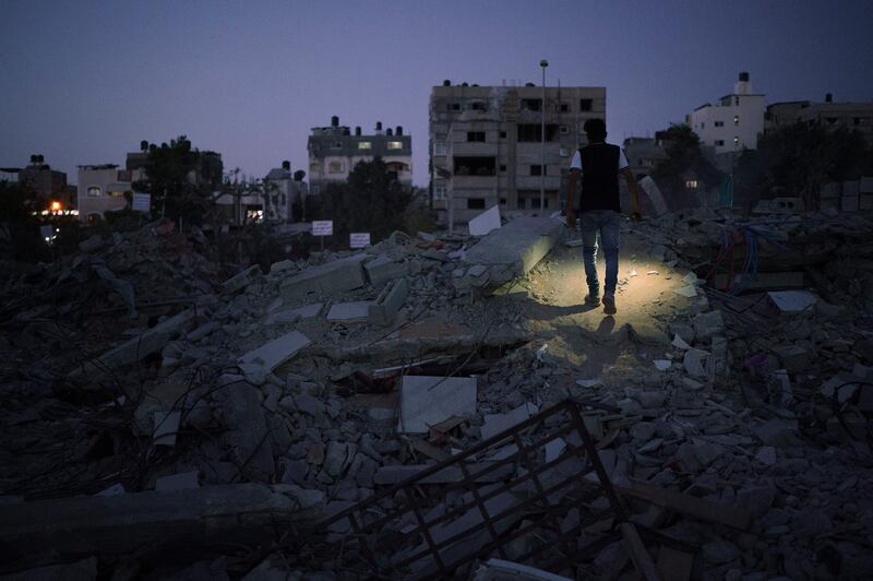 A man walks with a flashlight as he searches for valuables from the debris of a building destroyed during an 11-day war between Israel and Hamas, in Beit Lahia, northern Gaza Strip. AP Photo