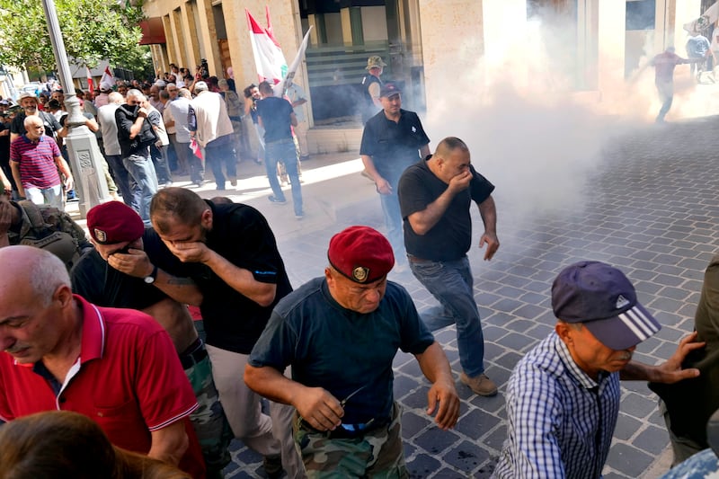 Retired army members run from tear gas fired by riot police. AP