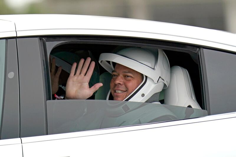 Bob Behnken waves as he and fellow crew member Doug Hurley ride back from Pad 39-A after their mission was delayed by stormy weather. AP