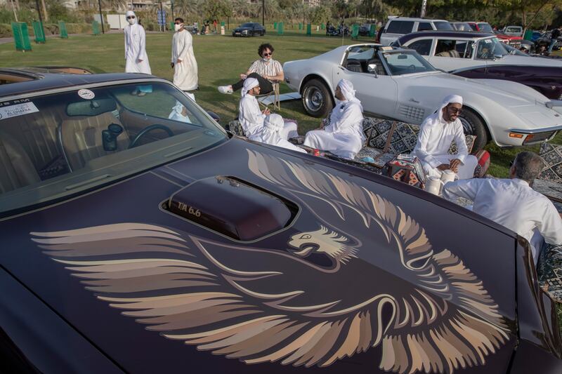 Visitors enjoy a picnic by a Pontiac Trans Am.