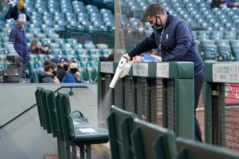 A worker sprays seats in the Seattle Mariners' dugout as a precaution against Covid-19 before a baseball game against the Chicago White Sox in the US. AP Photo