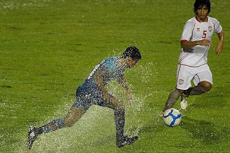Indian footballer Mehtab Hossain struggles to dribble through the monsoon, with the UAE's Amer Abdulrehman looking on.

Manan Vatsyayana / AFP