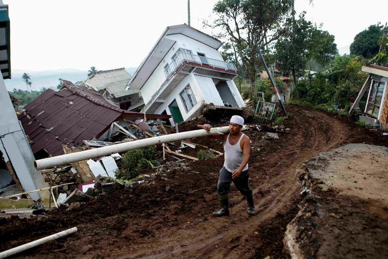 Opik Goparudin, 67, carries a duct near destroyed houses after Monday's earthquake hit Cianjur, West Java province, Indonesia. Reuters