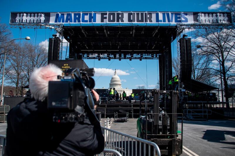 A cameraman films construction workers setting up the March For Our Lives stage ahead of the anti-gun rally in Washington, DC, on March 23, 2018. / AFP PHOTO / Andrew CABALLERO-REYNOLDS
