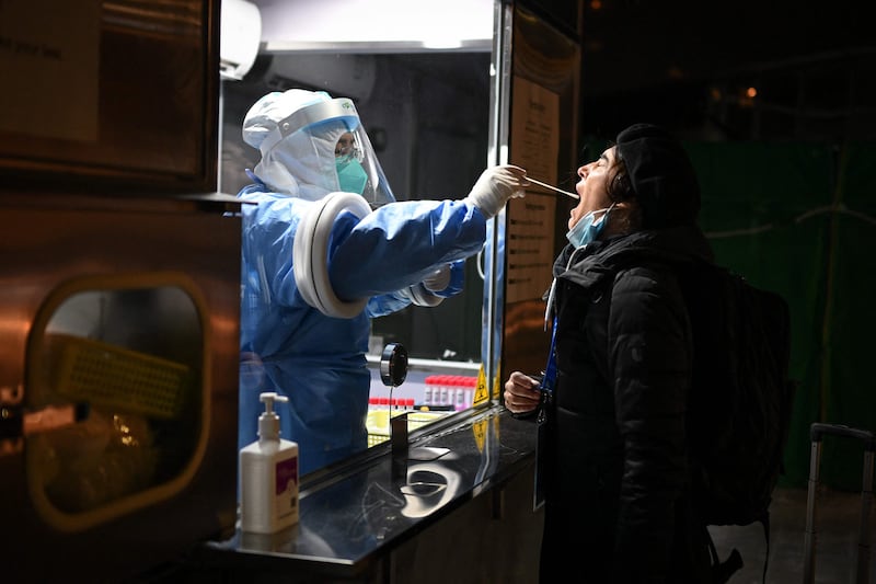 A health worker collects a swab sample from a member of the media before the start of the 2022 Winter Olympics in Beijing. AFP