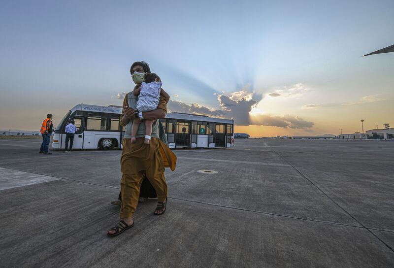 People flown from Afghanistan walk to board a flight bound for the US, at the Naval Air Station Sigonella, in Italy, on Saturday. AP