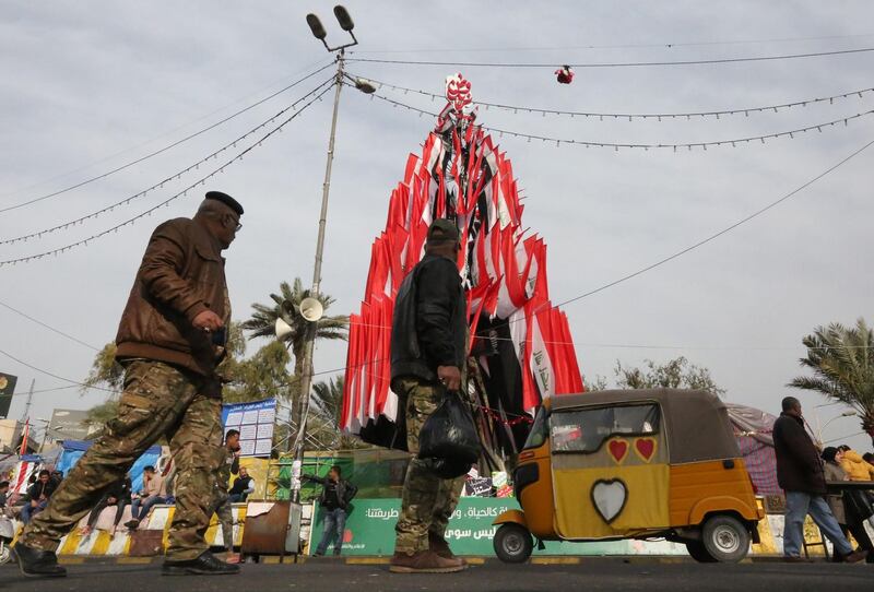 Iraqi men look at a Christmas tree made of national flags during ongoing anti-government demonstrations at Tahrir square in the capital Baghdad. AFP