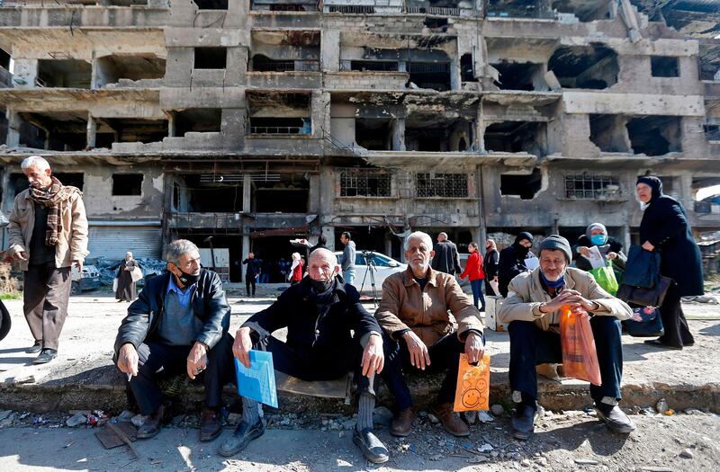 Residents of the Palestinian Yarmuk camp, on the southern outskirts of the Syrian capital Damascus, walk past destroyed buildings. AFP