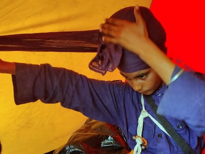 Fatesh Singh, 14, tying his turban. The teenager joined the warrior community four months ago and has since been stationed at Singhu border with community leaders and peers guarding the agitating farmers. Taniya Dutta for The National