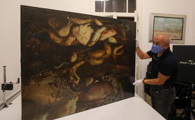 Gaby Maamary, a Lebanese artwork conservation specialist, examines a 17th-century painting by Italian painter Elena Recco, damaged in the Beirut port blast, at his studio in the capital Beirut on September 17, 2020. The blast at the capital's port on August 4 killed more than 190 people, and wounded thousands more as it sent lethal shockwaves pummelling through the city. But it also ravaged dozens of the capital's mot cherished heritage buildings. / AFP / ANWAR AMRO
