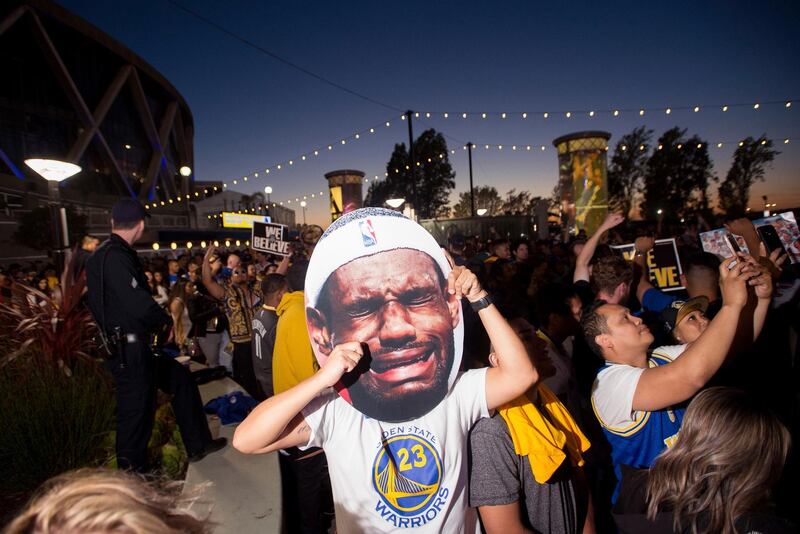 A man holds up an image of Cleveland Cavaliers' LeBron James crying as fans celebrate outside Oracle Arena in Oakland California. Josh Edelson / AP Photo