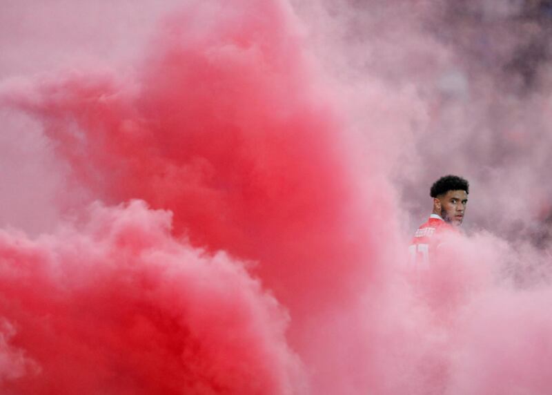 Wales' Tyler Roberts is surrounded by smoke after a flare is thrown on to the pitch by fans in their match against Denmark. Reuters