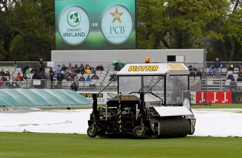 Groundsmen work on the wet pitch at Malahide as the start of play is delayed on the first day of the Test. Paul Faith / AFP