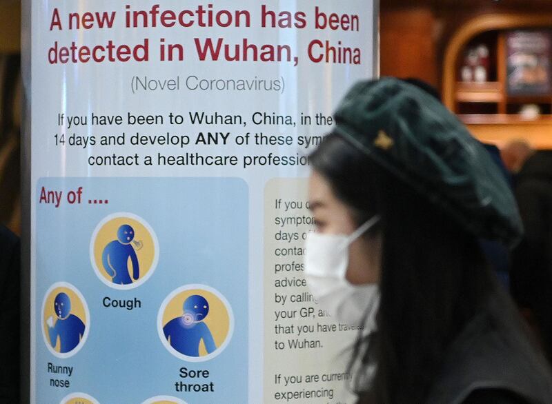 A woman wearing a face mask passes a health notice warning passengers arriving at London's Heathrow Airport about the virus.  AFP