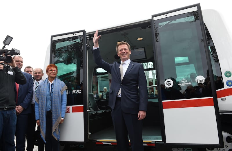 Richard Lutz, CEO of German railway company Deutsche Bahn, waves in front of the first German autonomous public transport bus during a presentation in Bad Birnbach, southern Germany, on October 25, 2017. 
German state-owned rail company Deutsche Bahn unveiled its first-ever driverless bus Wednesday, saying the shuttle will bring passengers through a picturesque spa town to the train station. The first autonomous minibus can transport six passengers. It will travel on a partial public transport route of 700 meters in the small town of Bad Birnbach Lower Bavaria. / AFP PHOTO / Christof STACHE