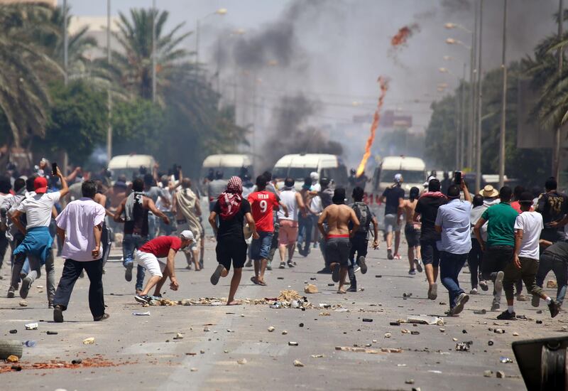 Tunisian protesters clash with security forces as they demonstrate in the southern city of  Tataouine on June 22, 2020 demanding authorities make good on a 2017 promise to provide jobs in the gas and oil sector to thousands of unemployed. Tunisian security forces clashed for a second day with protesters demanding jobs and the release of an activist in Tunisia's marginalised south, after weeks of tensions. The protests come as Tunisia, until now largely spared the worst of the novel coronavirus, faces tensions within its coalition government and the impact of restrictions imposed to combat the spread of the pandemic that have accentuated inequalities. / AFP / FATHI NASRI

