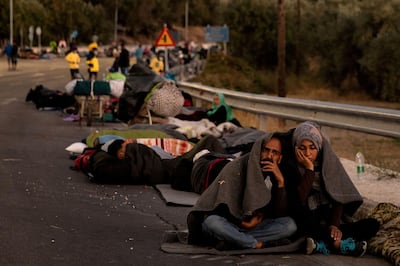 FILE PHOTO: A couple sits covered with a blanket as refugees and migrants camp on a road following a fire at the Moria camp on the island of Lesbos, Greece, September 10, 2020. REUTERS/Alkis Konstantinidis/File Photo/File Photo