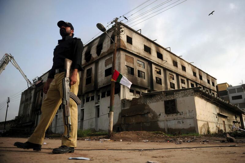 A Pakistani policeman stands guard outside the burnt-out garment factory in Karachi on September 14, 2012. Three factory-owners facing murder charges over the deaths of 289 people in a huge fire in Karachi handed themselves in to court on September 14 to request pre-arrest bail, their lawyer said.    Workers burned to death or suffocated in the massive blaze that engulfed Ali Enterprises clothing factory, which made ready-to-wear clothes for export to Western retailers, on Tuesday evening. AFP PHOTO / ASIF HASSAN (Photo by ASIF HASSAN / AFP)