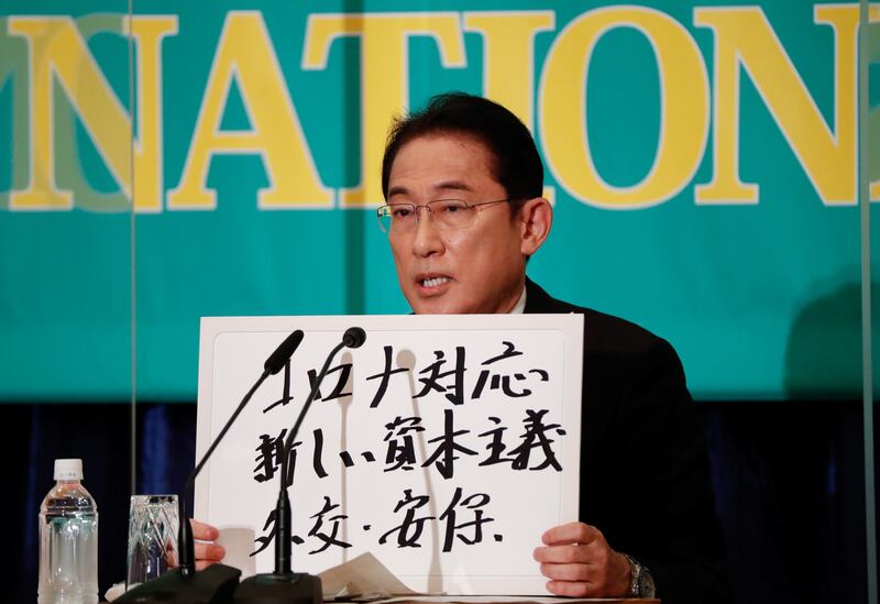 Japanese Prime Minister Fumio Kishida holds up a placard reading 'Corona Disease Countermeasures, New Capitalism, Diplomacy and Security' at the Japan National Press Club in Tokyo last week. Reuters