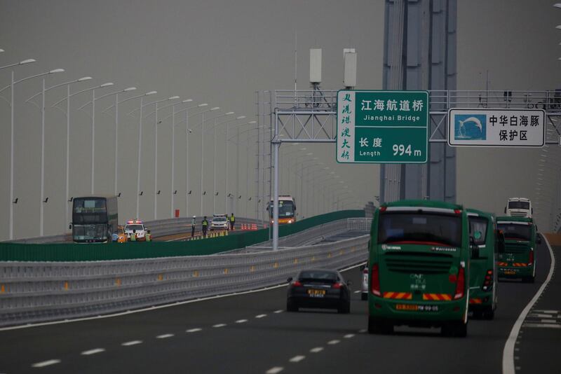 Policemen stand near a double-decker bus stopped on the other side of the road.