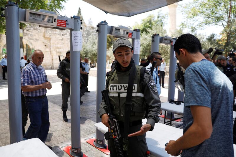 An Israeli border police officer asks to check the identity of a Palestinian man next to newly installed metal detectors at an entrance to the compound known to Muslims as Noble Sanctuary and to Jews as Temple Mount to be reopened, in Jerusalem's Old City. Ronen Zvulun / Reuters