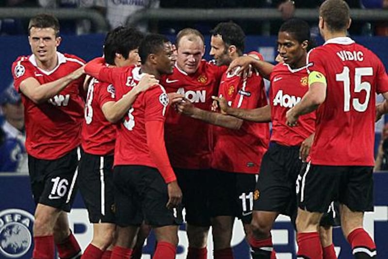 Manchester United players rush to congratulate Wayne Rooney, centre, scoring their second goal against Schalke in Germany.