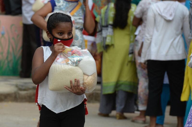 A girl carries food distributed for people in need during a coronavirus lockdown, at Saint Marys Basilica in Secunderabad, India. AFP
