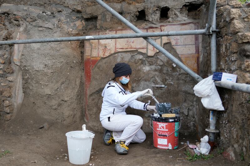 A restorer performs deep consolidation of an unearthed wall.