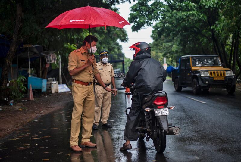 A police officer in Kochi, Kerala state, shelters from the rain as he enforces a lockdown to curb the spread of the coronavirus. AP Photo