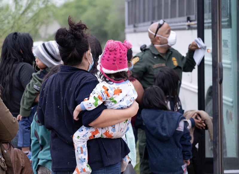 A woman holds a young girl as she's about to board a US Border Patrol bus. The vast majority of migrants apprehended by US border patrol are returned to Mexico immediately under Title 42. Willy Lowry/ The National