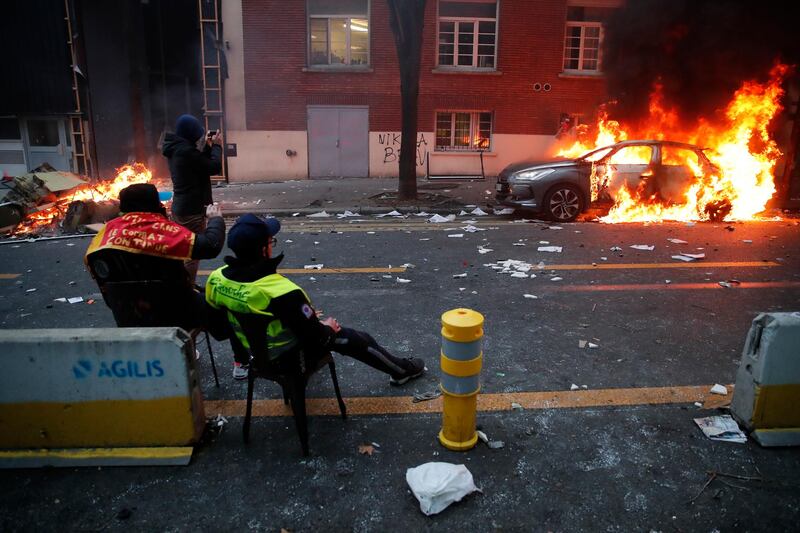 Protesters sit in front of burning cars during a demonstration in Paris. AP Photo