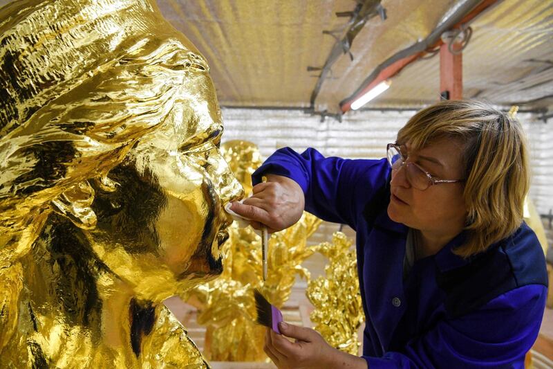 A restorater works on a gilded bronze statue of the Friendship of Nations fountain in Moscow, Russia. AFP