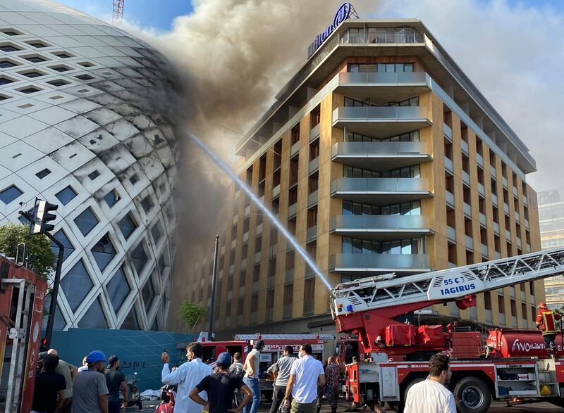 People gather next of firefighters who are extinguishing a building under construction that was the work of late Iraq-born British architect Zaha Hadid, in Beirut, Lebanon. AP Photo