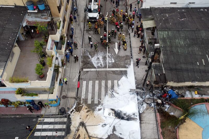 An aerial view of firefighters, police and rescuers working at the site where a light aircraft crashed and killed two people in Guayaquil, Ecuador.  AFP