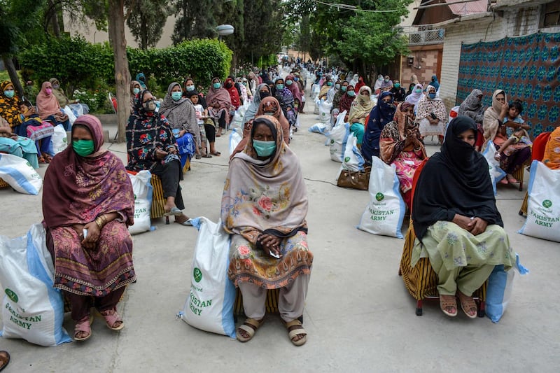 People sit maintaining social distancing as Frontier Corps (FC) personnel distribute food on a street during a government-imposed nationwide lockdown as a preventive measure against the coronavirus, in Quetta. AFP
