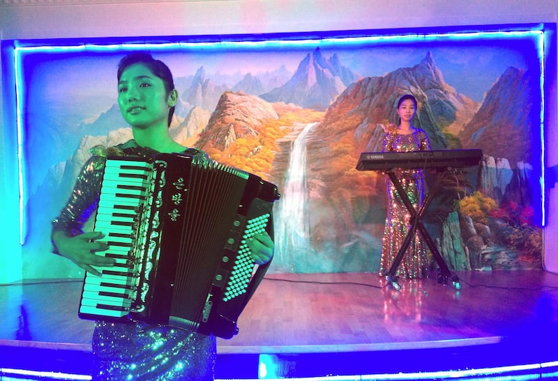 In this Tuesday, July 25, 2017 photo, Korean waitresses play music at the Pyongyang Okryu-Gwan North Korean Restaurant in Dubai, United Arab Emirates. From state-run restaurants to construction sites, North Korean workers in Kuwait, Oman, Qatar and the United Arab Emirates face conditions akin to forced labor while being spied on by planted intelligence officers, eating little food and suffering physical abuse, authorities say. (AP Photo/Kamran Jebreili)