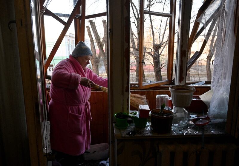 An elderly woman sweeps glass broken from windows in her flat after the explosion of a downed Russian drone in a yard between residential buildings in Kyiv. AFP