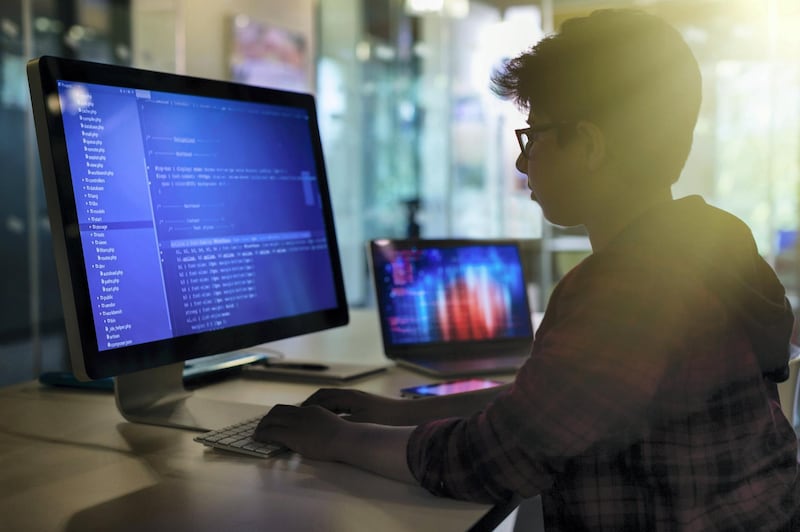 Boy student programming at computer in dark classroom